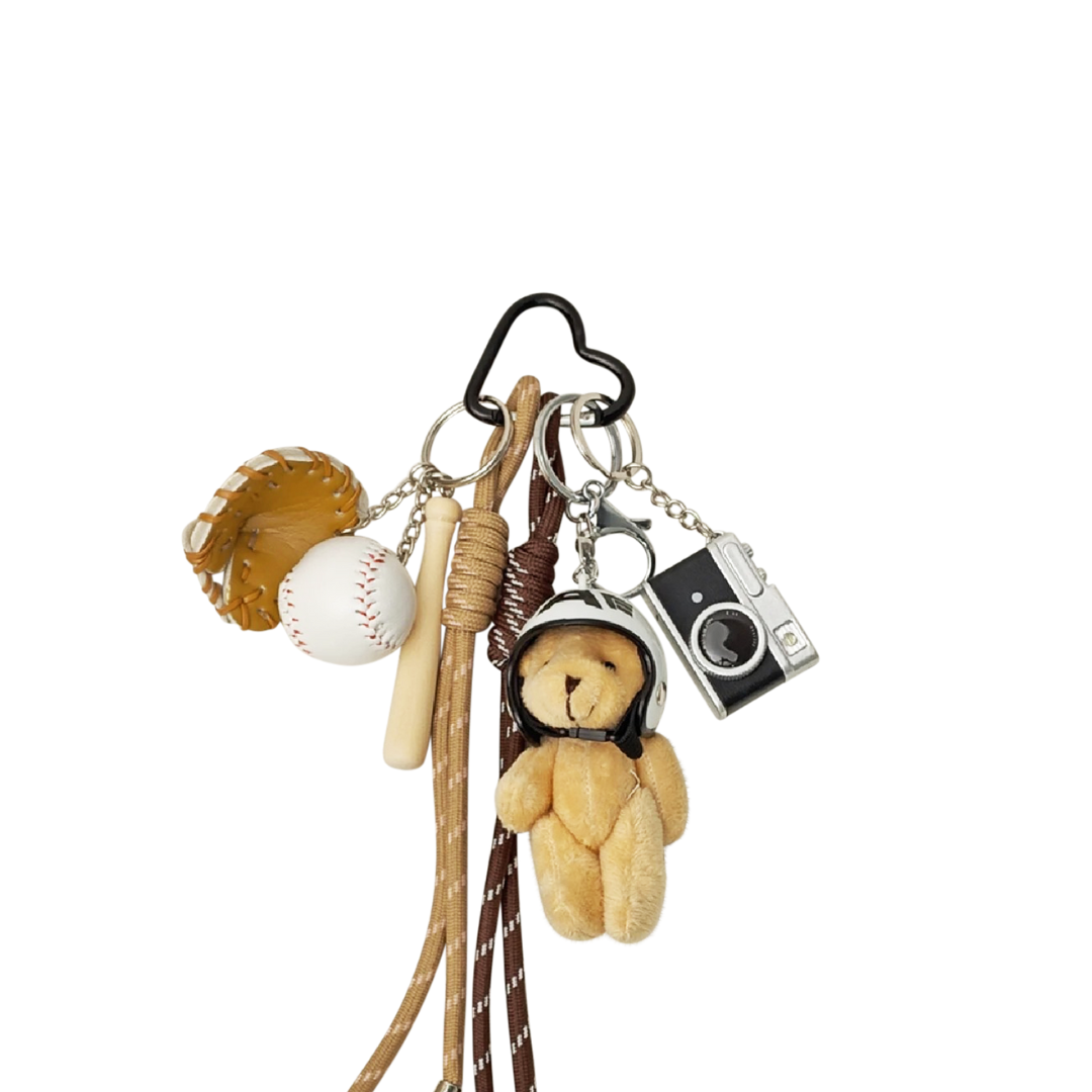 Beige plush teddy bear bag charm with baseball bat, glove, and camera components hanging from a keychain.