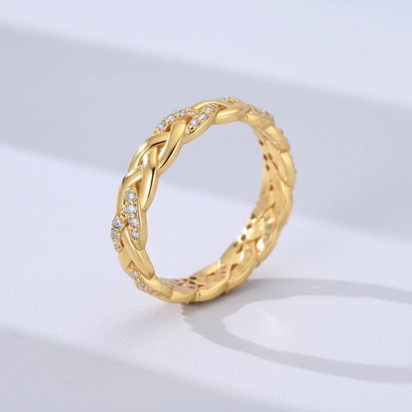 Gold braided ring with small diamonds on a light gray background