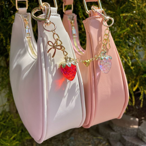 A bag charm with pink and white strawberrys on them