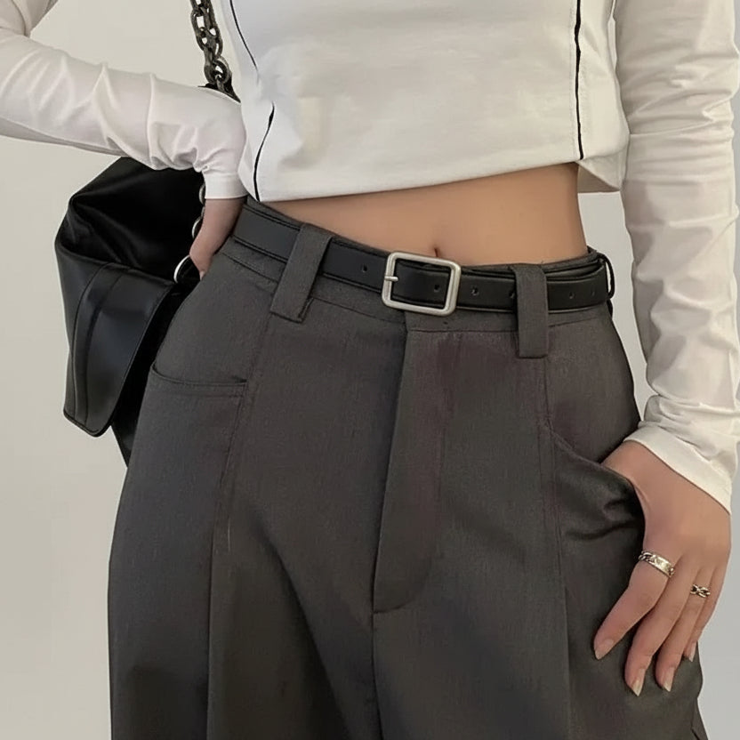 Person wearing a white long-sleeve top and gray pants with a black belt.