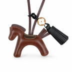 Brown leather horse-shaped keychain with a tassel on a white background