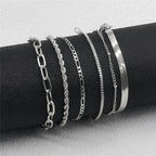 Set of silver bracelets on a black cylindrical object against a light gray background