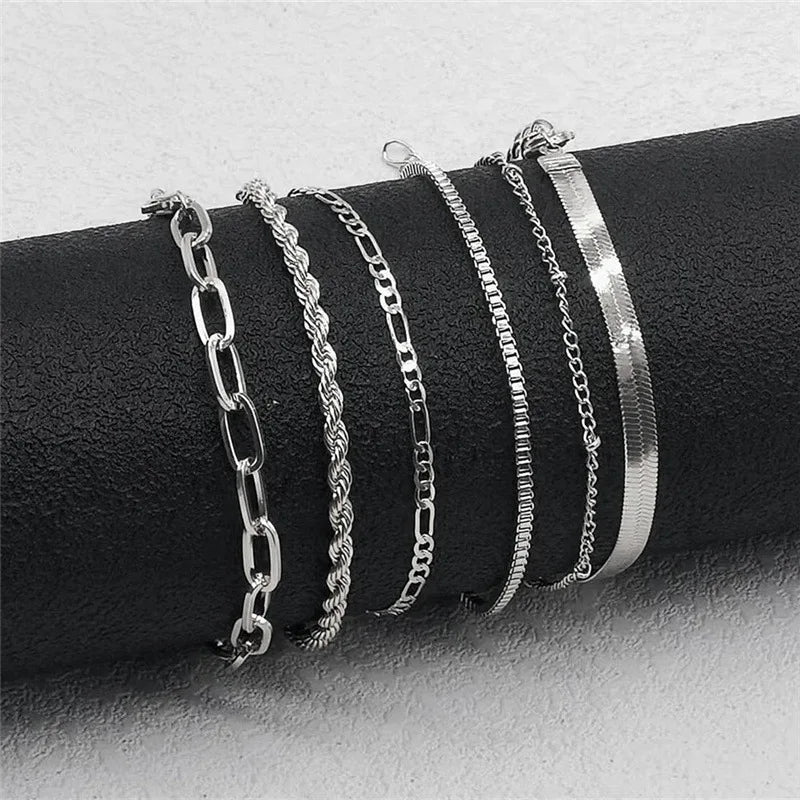 Set of silver bracelets on a black cylindrical object against a light gray background