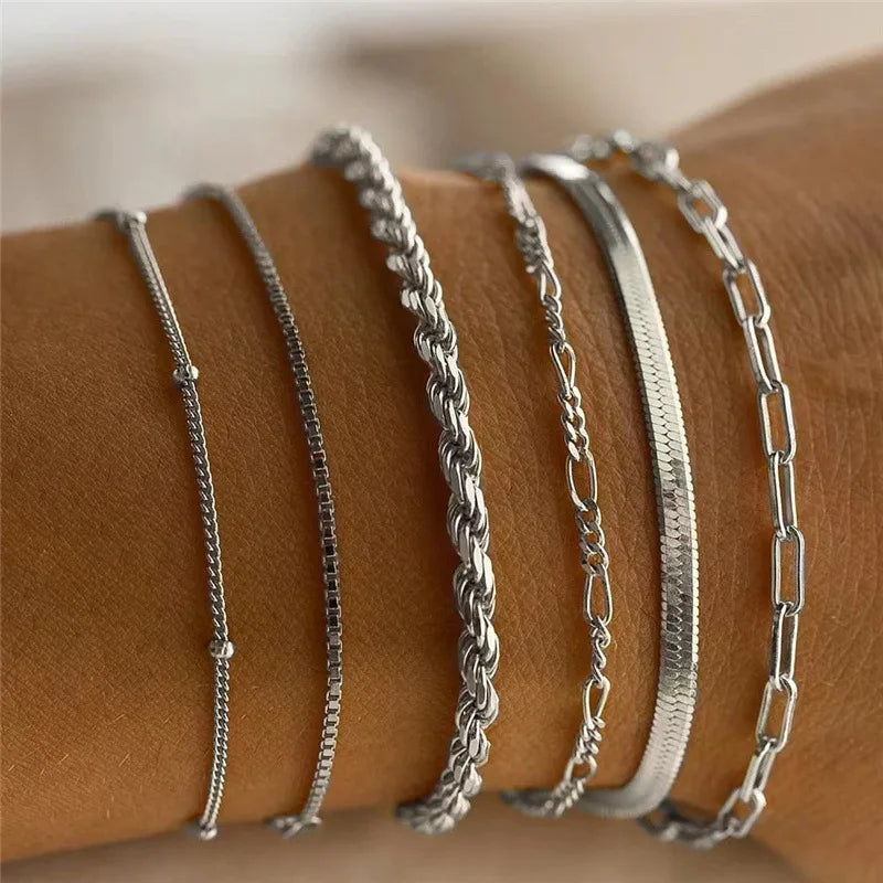 Silver chains on a person's wrist against a neutral background