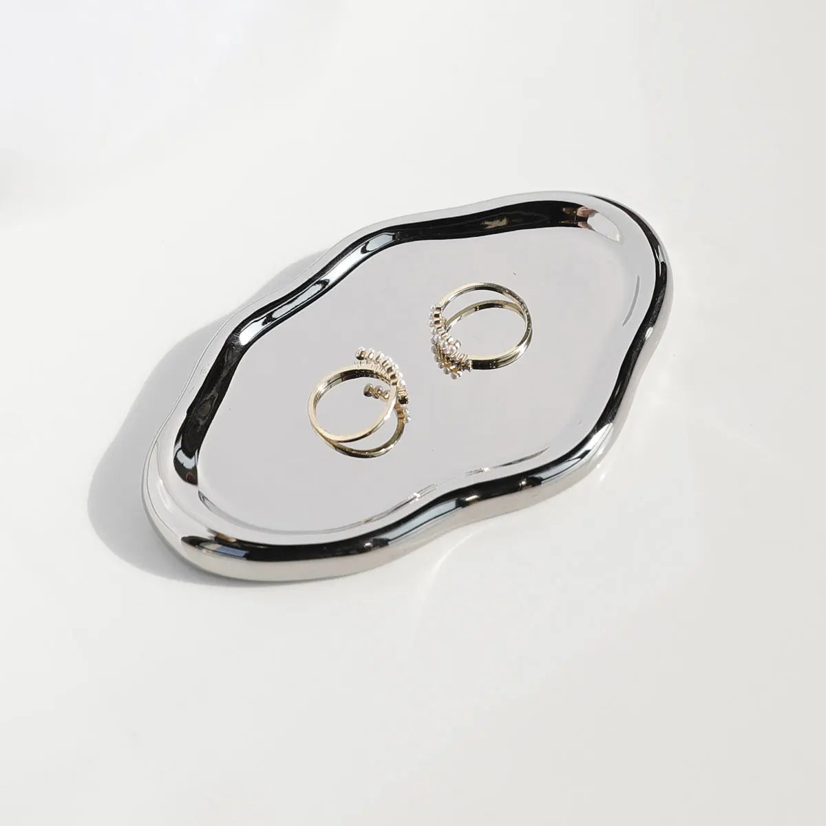 Silver ring dish with three rings on a white background