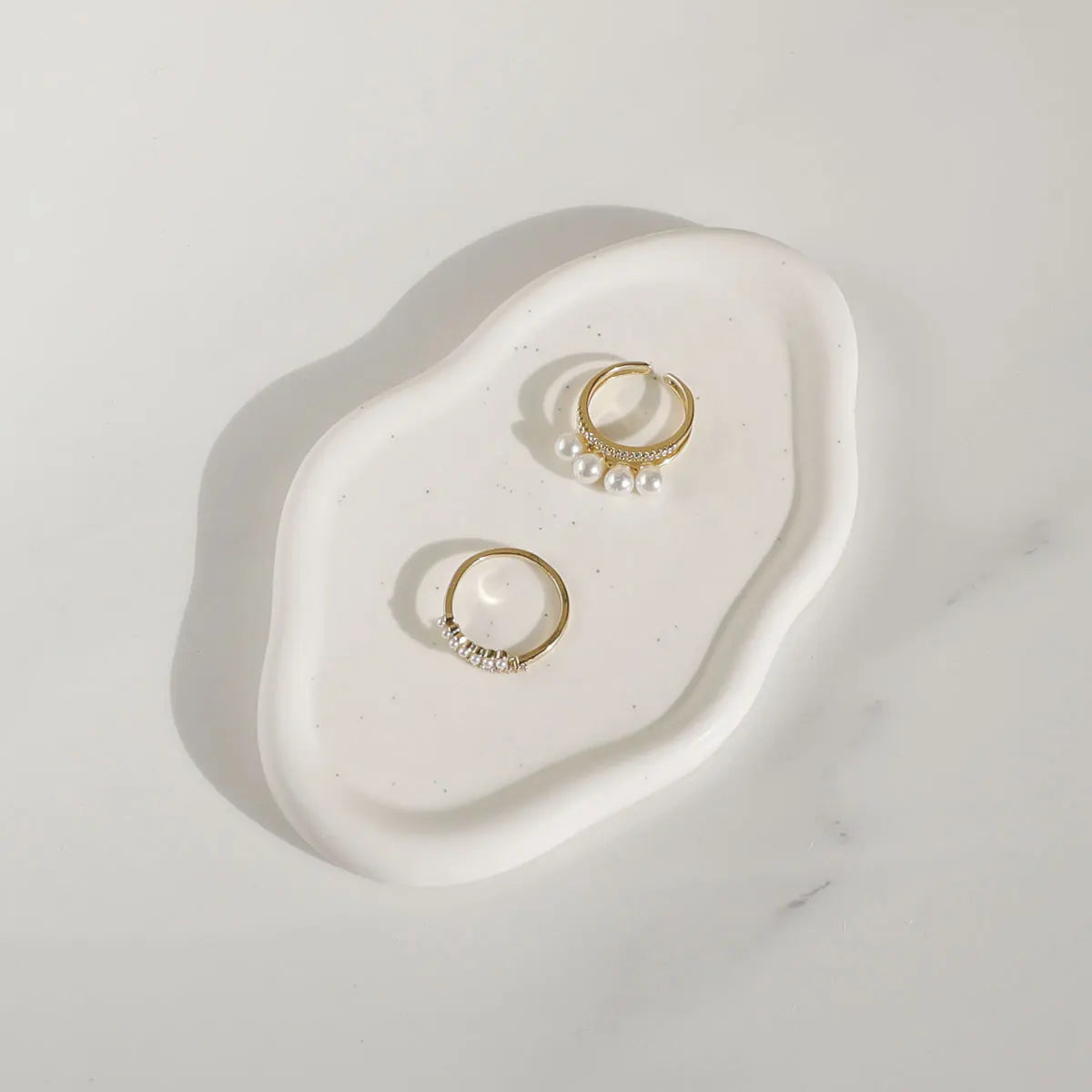 Two gold hoop earrings with pearls on a white stone surface