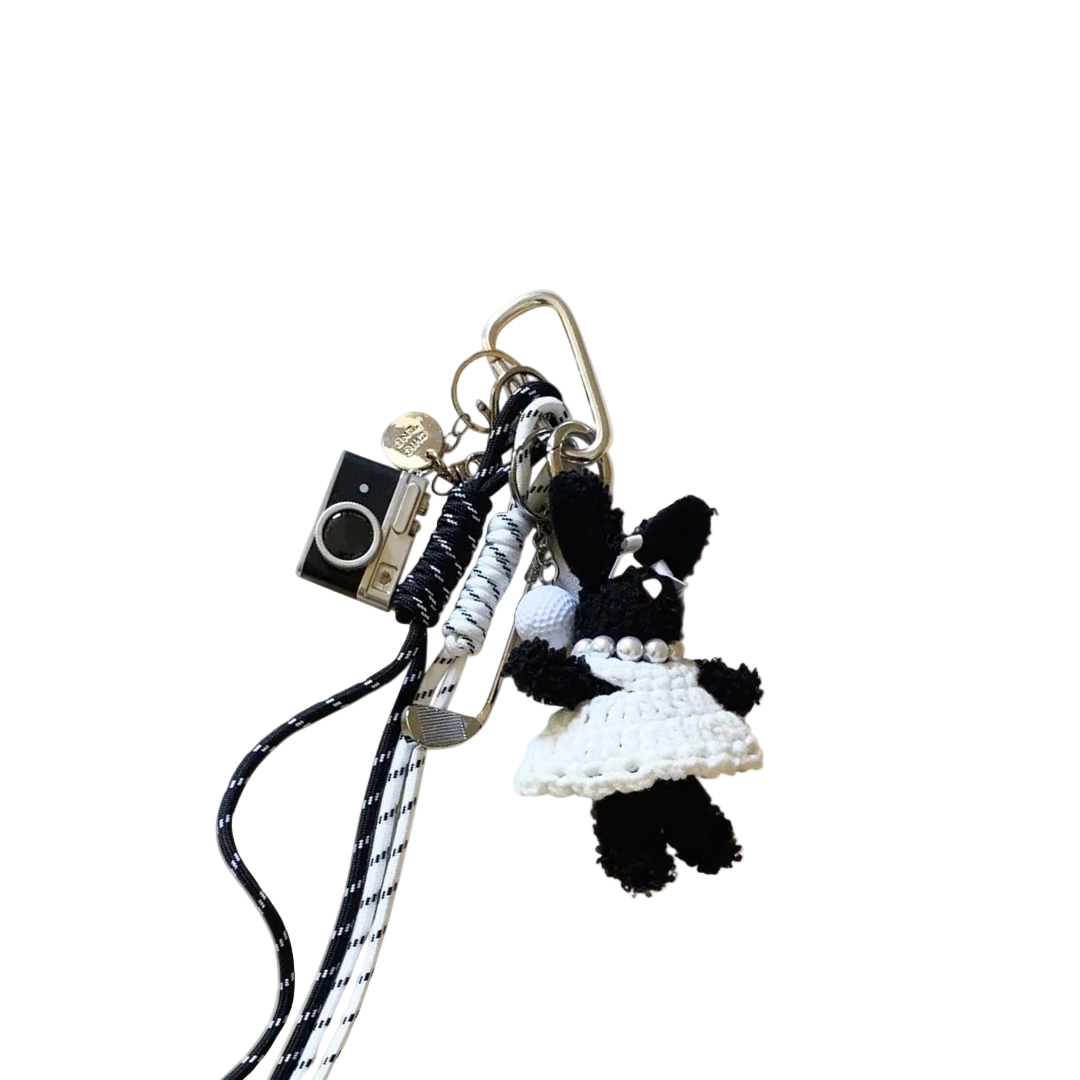 Keychain with a black bunny wearing a white dress charm and camera pendant on a white background