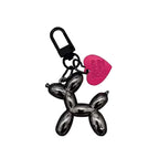 Keychain shaped like a balloon dog with a pink heart tag on a light gray background