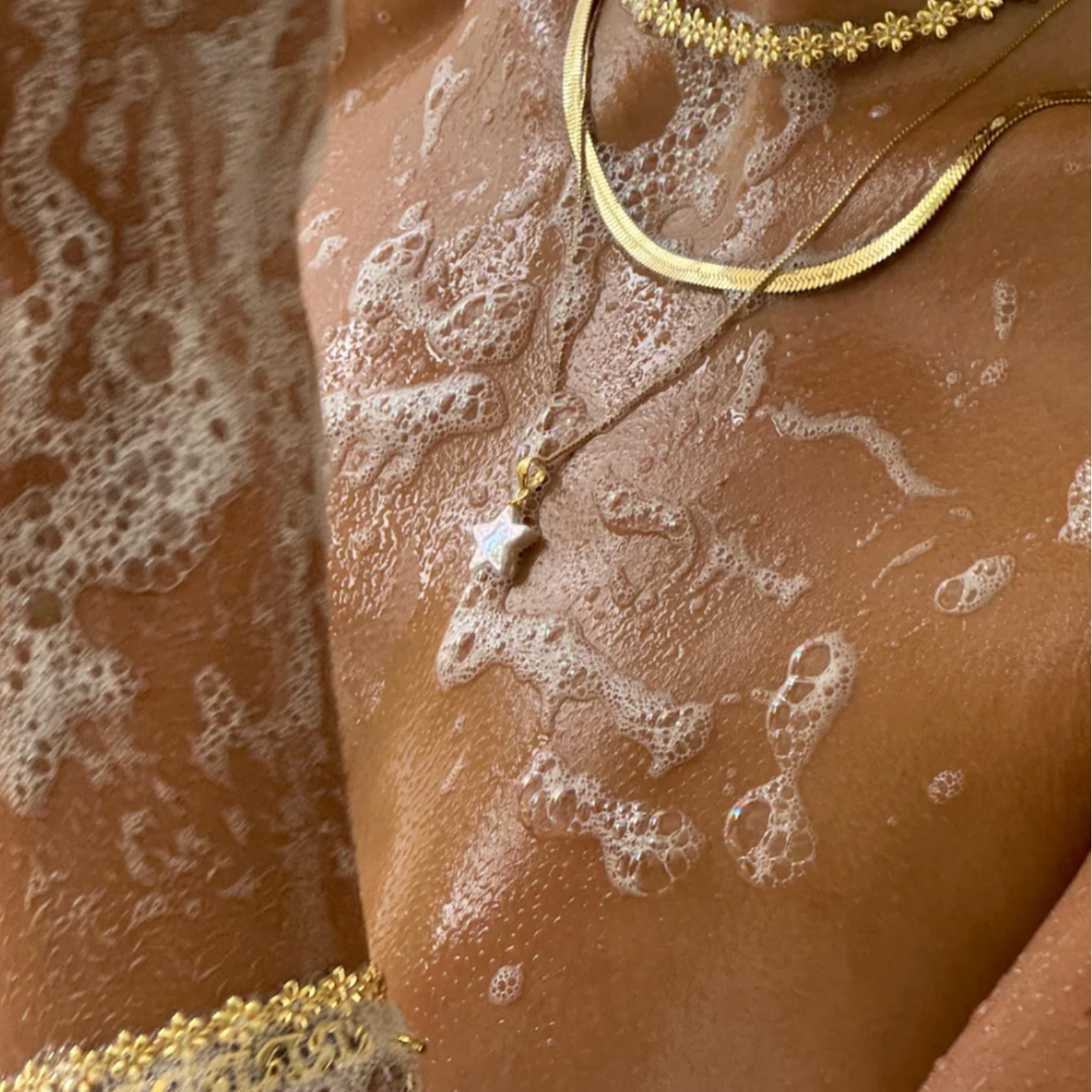 Close-up of a person wearing gold necklaces with a textured background