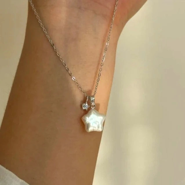 Star-shaped pendant necklace on a person's neck against a neutral background
