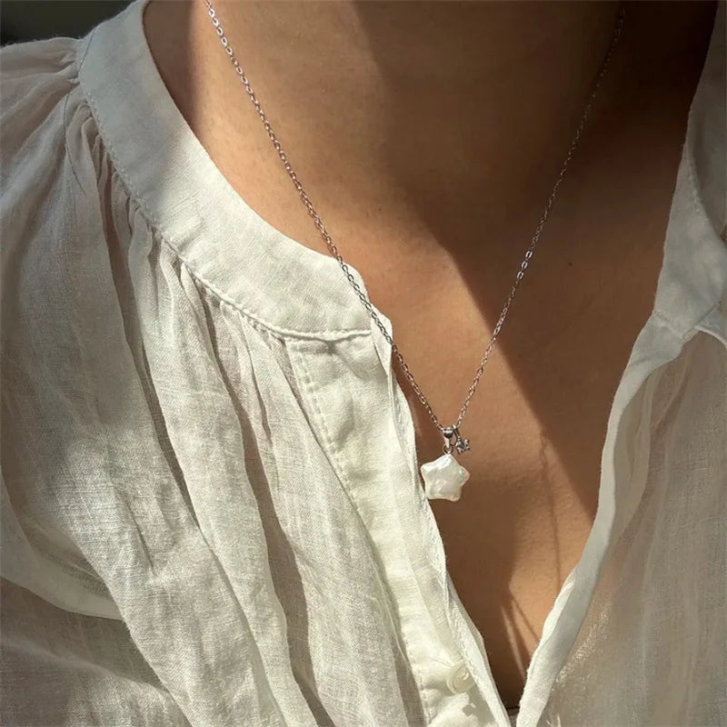 Necklace with a pendant worn by a person in a light-colored shirt.
