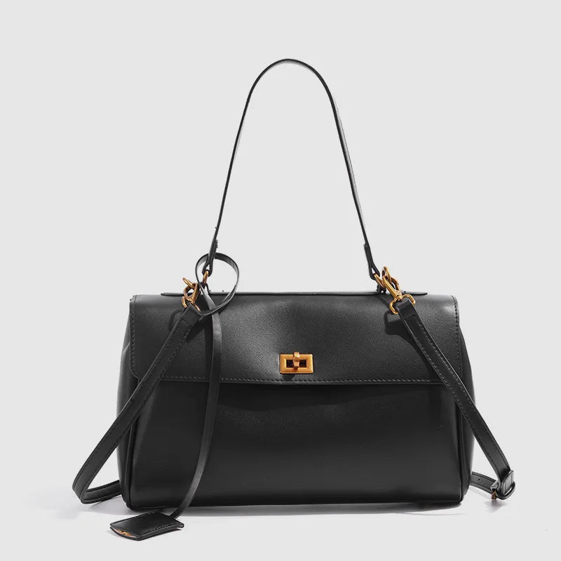 Black handbag with a gold clasp on a light gray background