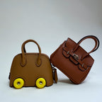 Two brown handbags, one with wheels and yellow tires, on a white background