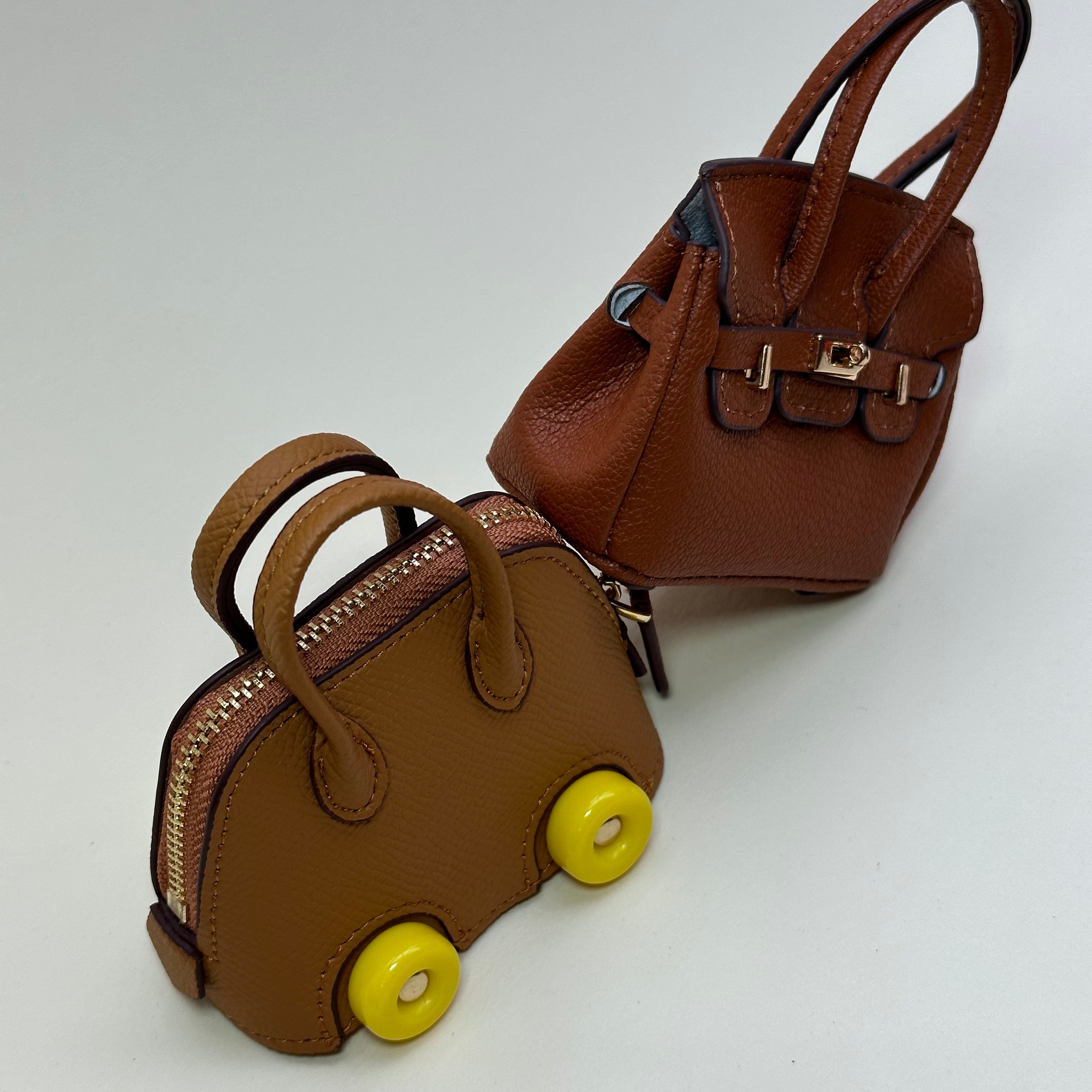 Two brown leather bags with yellow accents on a white background