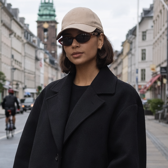 Woman in black coat and white sneakers walking on a city street