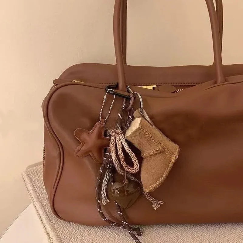 Brown leather handbag with decorative elements on a beige surface