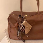 Brown leather handbag with decorative elements on a beige surface