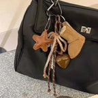 Keychain with star, heart, and boot-shaped charms attached to a black bag.