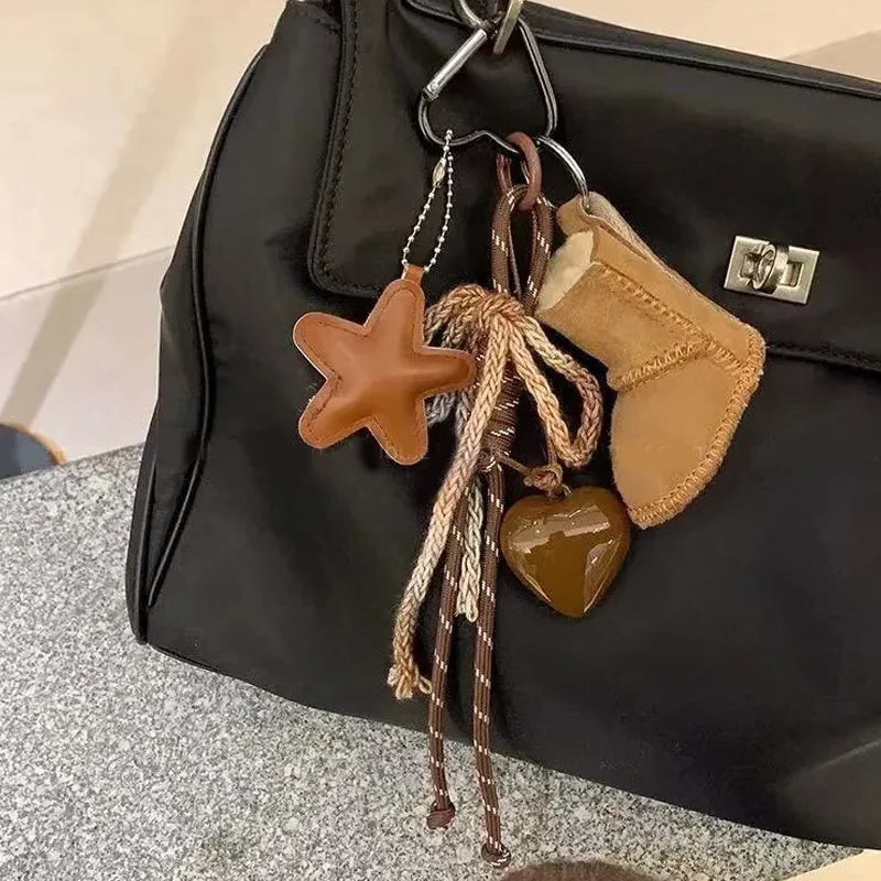 Keychain with star, heart, and boot-shaped charms attached to a black bag.