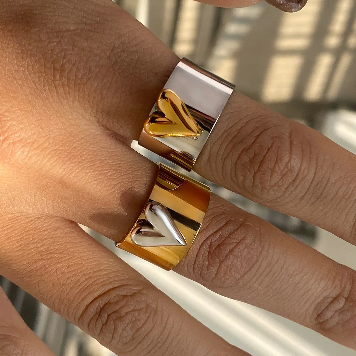 Gold and silver ring on a person's finger with a blurred background