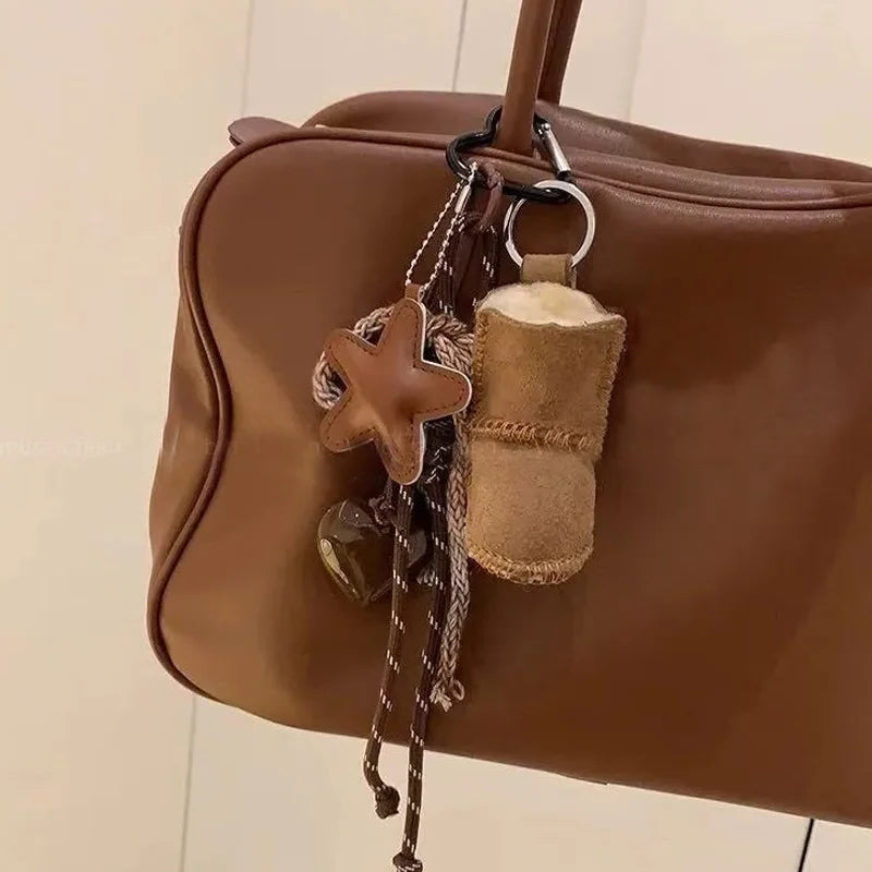 Brown leather handbag with decorative keychain on a neutral background