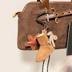 Brown leather bag with a keychain featuring a star and boot design on a neutral background