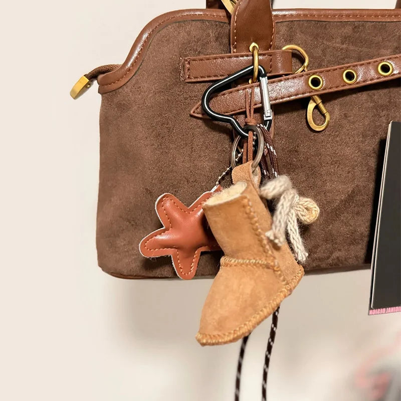 Brown leather bag with a keychain featuring a star and boot design on a neutral background