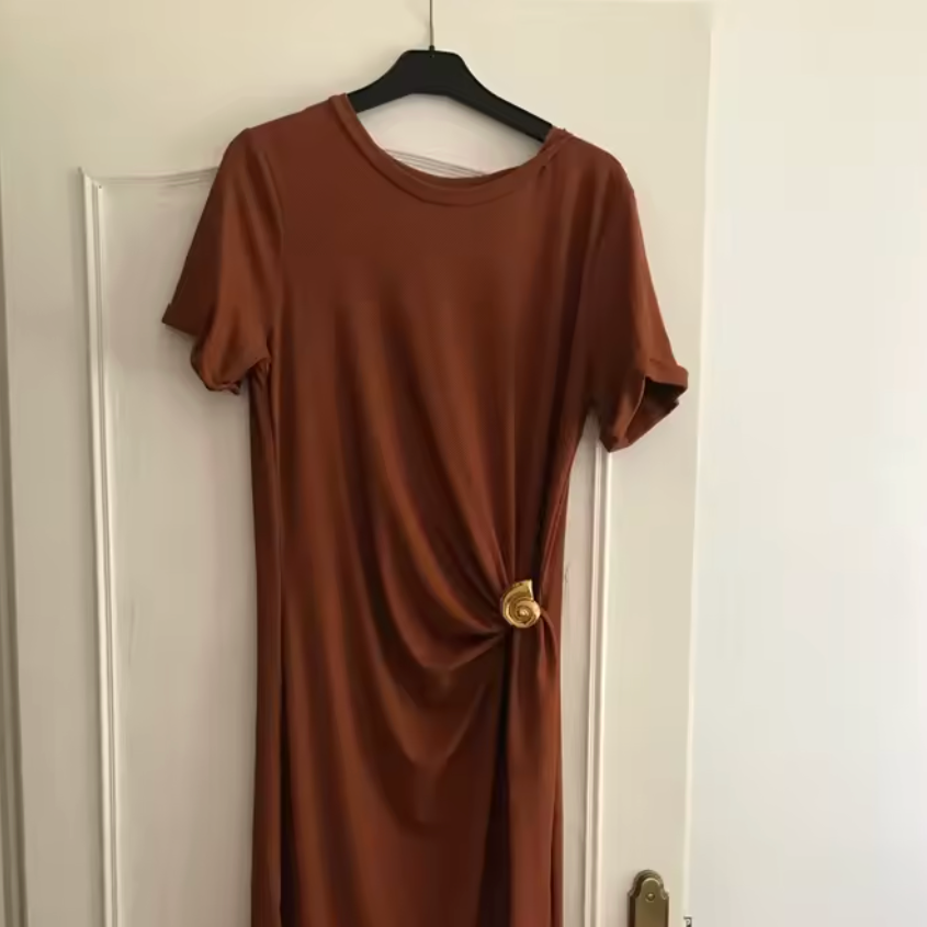 Brown dress on a hanger against a white door