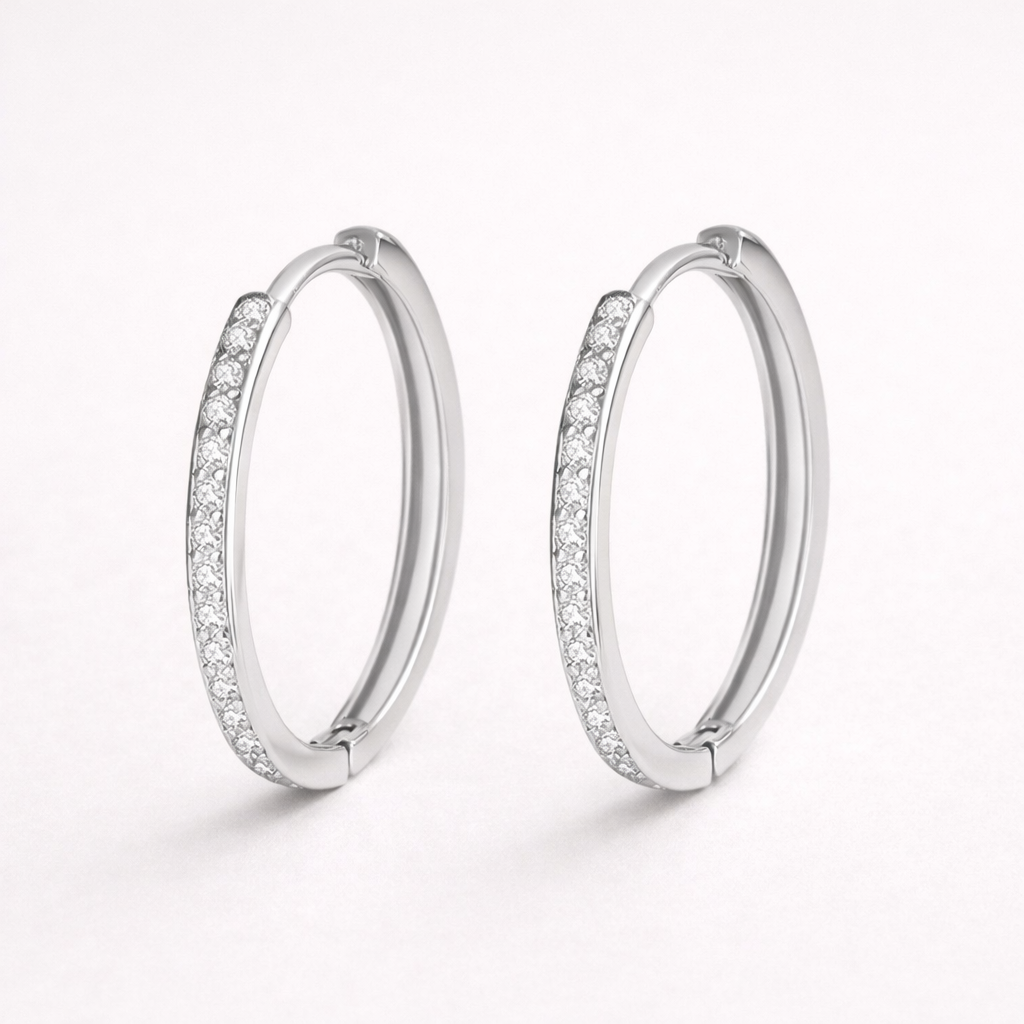 Pair of silver hoop earrings with embedded stones on a white background