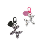 Metallic balloon dog keychains with pink and black carabiners on a white background