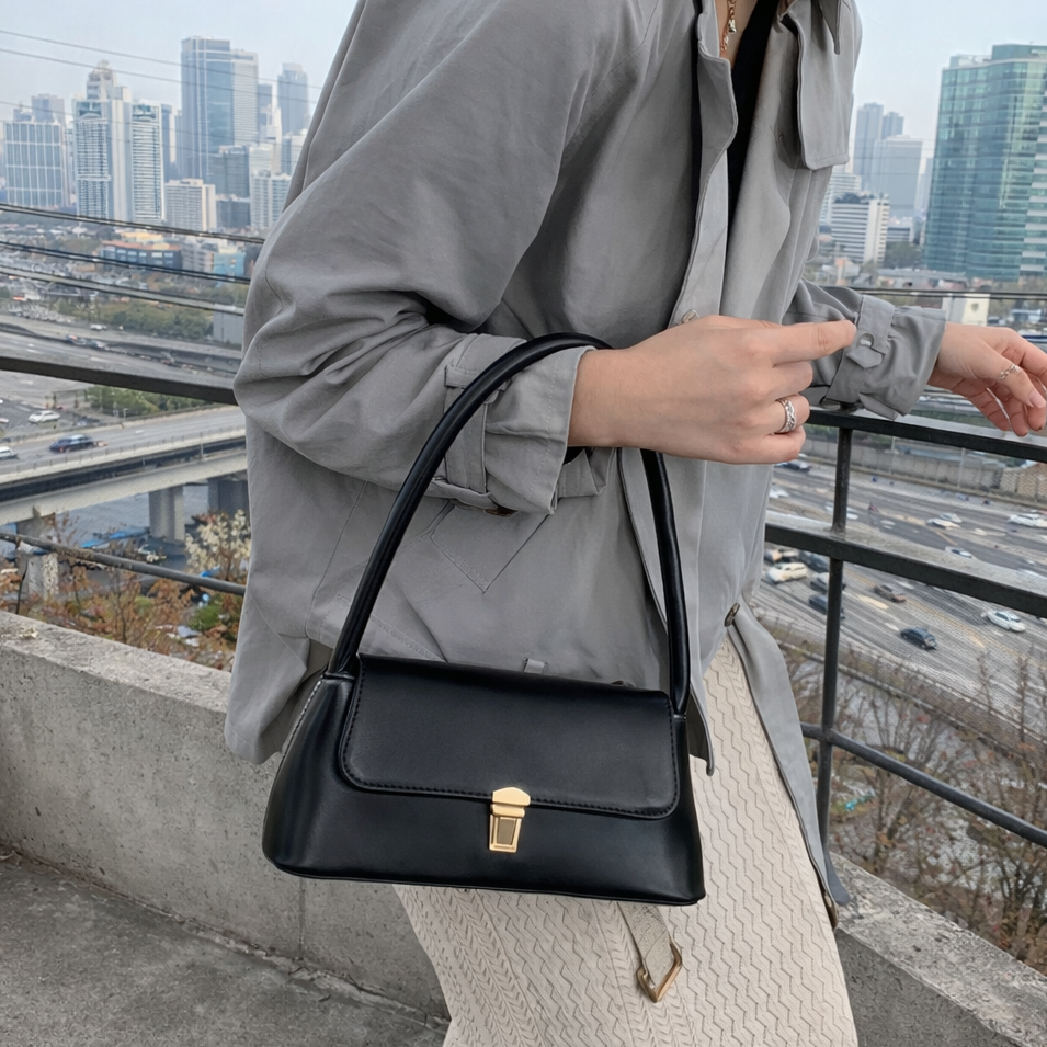 Person holding a black handbag with a cityscape in the background
