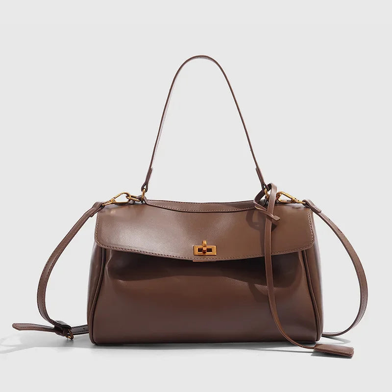 Brown leather handbag with a gold clasp on a light gray background