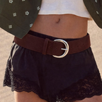 Person wearing a white top, black lace shorts, and a brown belt with a large buckle.