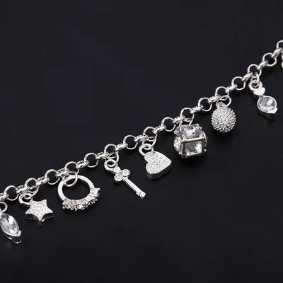 Silver charm bracelet with various charms on a black background