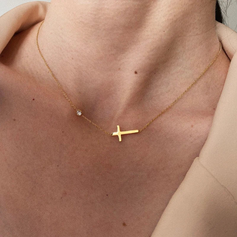 Gold necklace with a cross pendant on a person's neck