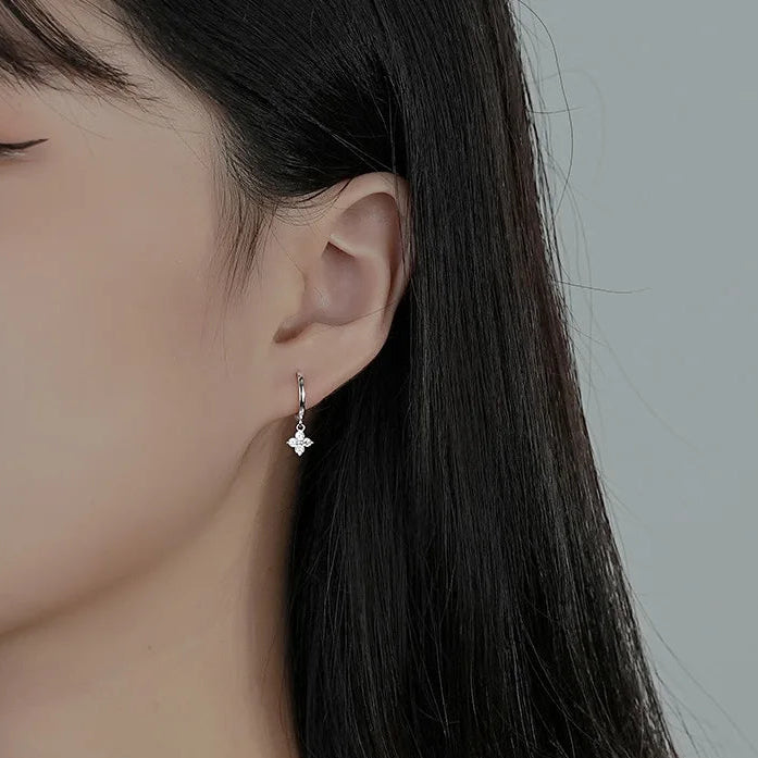 Close-up of a person wearing a silver earring with a gray background