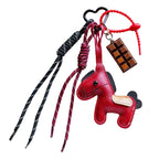 Red horse-shaped keychain with braided straps on a dark surface