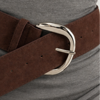 Brown belt with a silver buckle worn by a person on a gray background