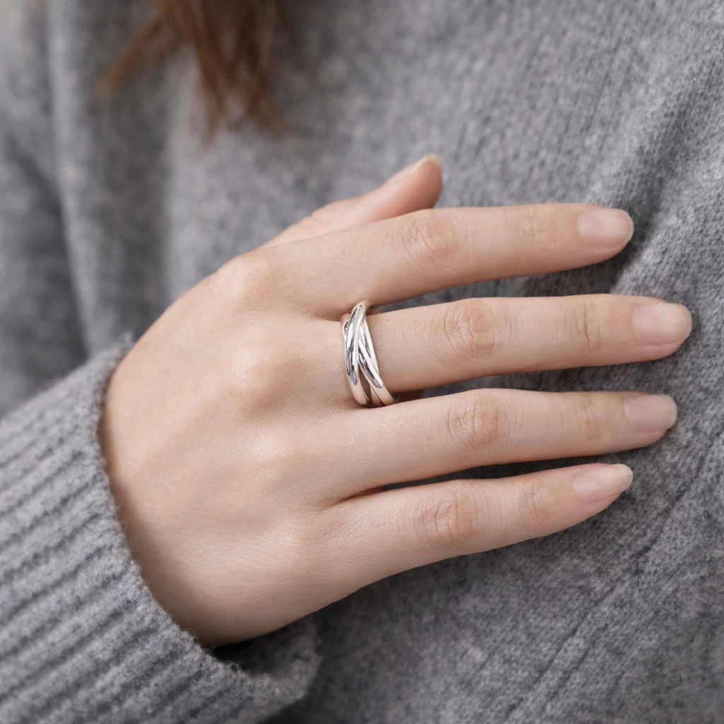 Hand wearing a silver ring on a gray textured background