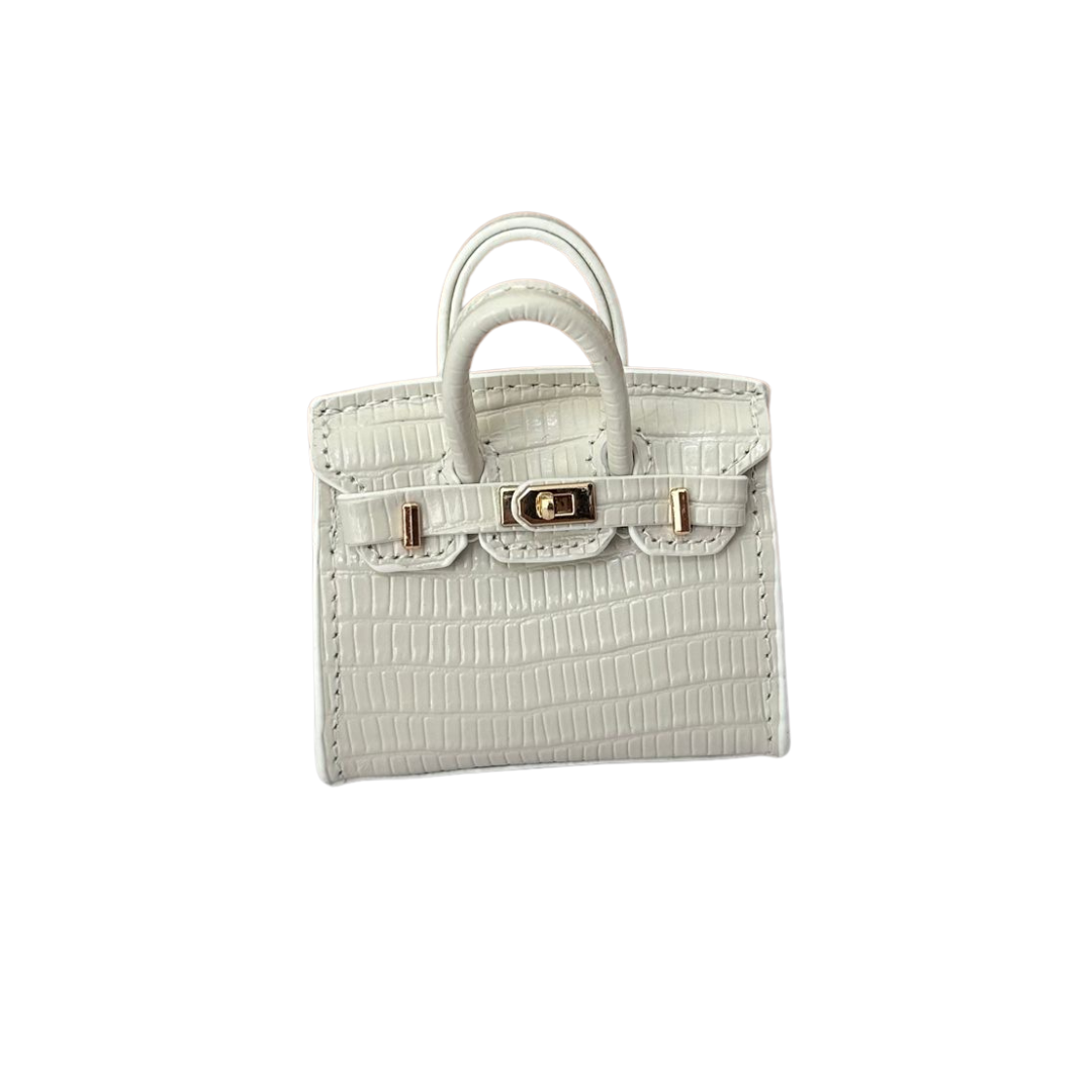 White genuine leather structured charm with a fine pebbled/grained texture and top handle.
