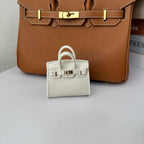 White genuine leather structured charm with a fine pebbled/grained texture and top handle.