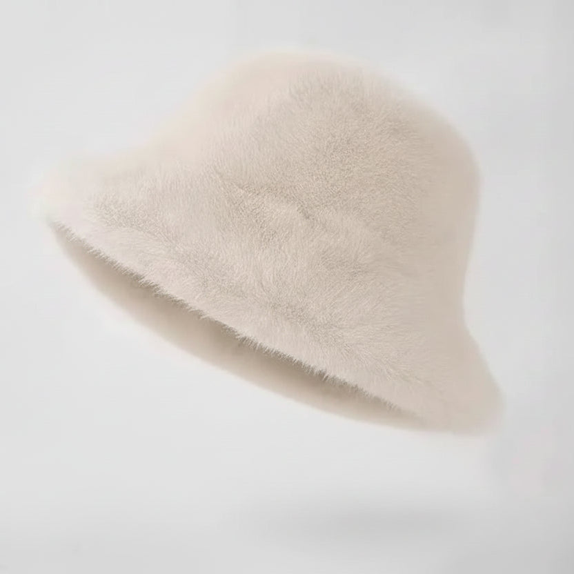 Cream-colored fur hat on a wooden stand against a white background
