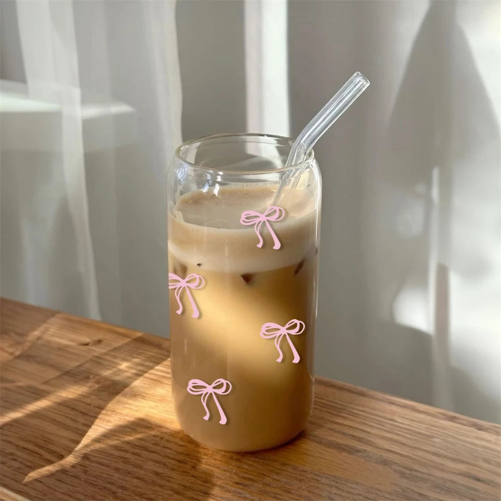 Glass of iced coffee with a straw on a wooden surface, decorated with pink bow-shaped stickers.