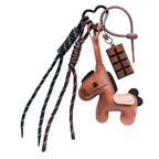 Leather keychain with horse design and chocolate bar charm on a dark surface.
