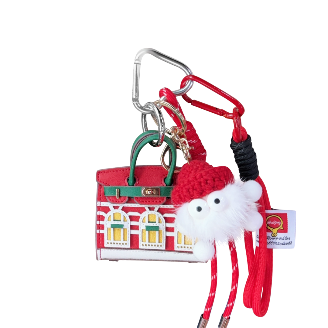 Keychain with red house mini handbag charm, chrstmas decoration, and red strap on a white background