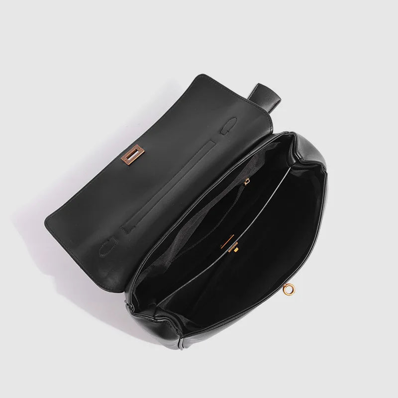 Black leather bag with gold hardware on a light gray background