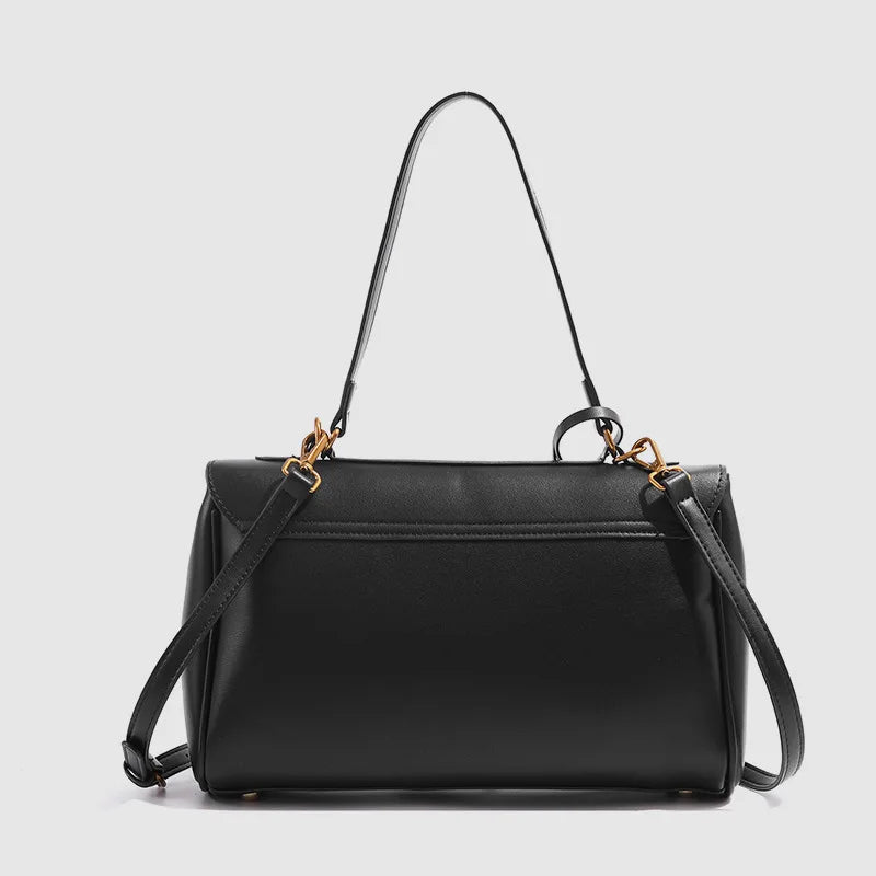Black handbag with gold hardware on a light gray background