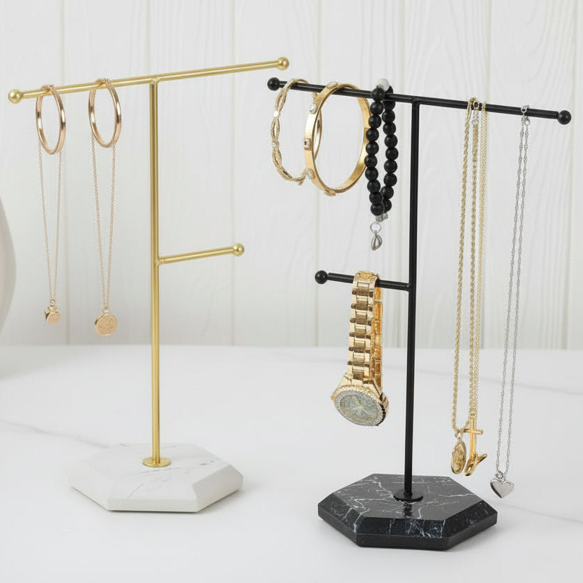 Jewelry stands with necklaces, bracelets, and a watch on a white surface.
