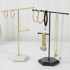 Jewelry stands with necklaces, bracelets, and a watch on a white surface.