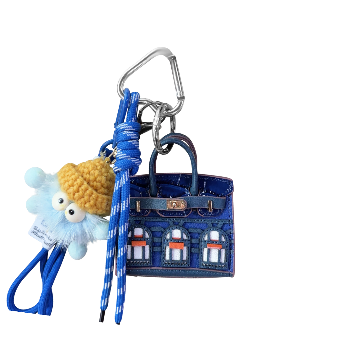 Blue leather structured mini bag charm shaped like a house, featuring decorative window panels and a top handle.